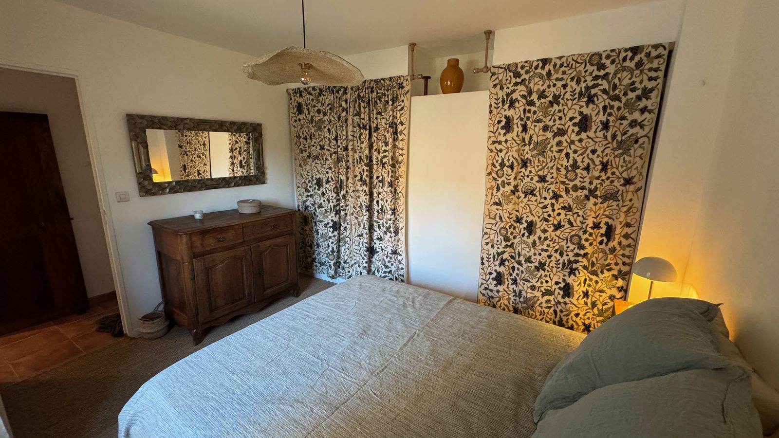 La chambre principale, lit en lin vert sauge et tentures florales