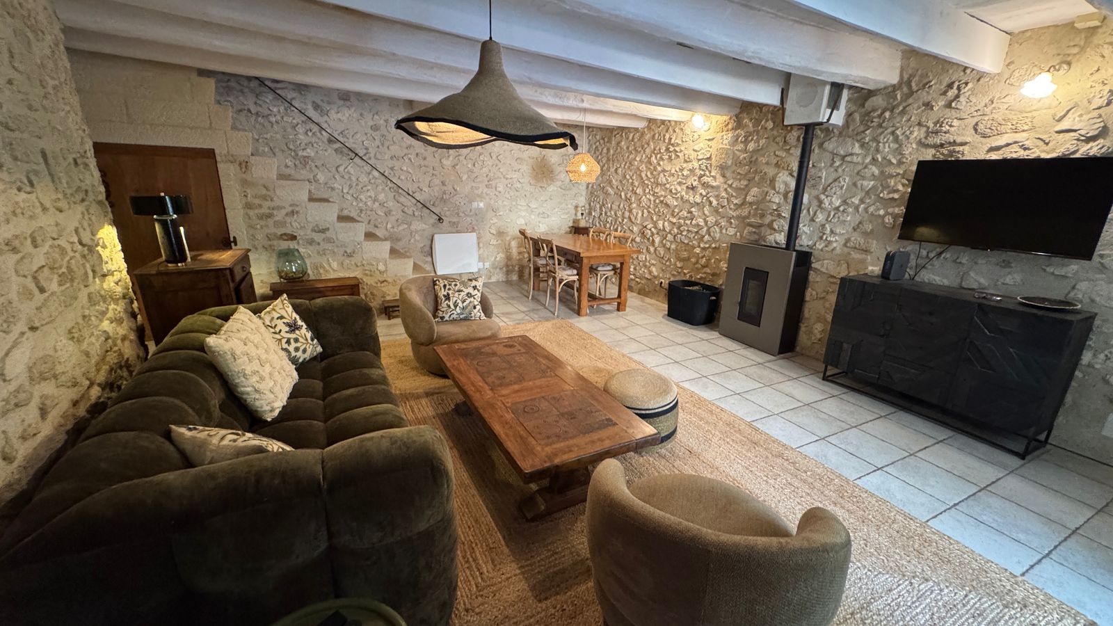 Le salon en pierre apparente, canapé en velours et table basse en bois patiné